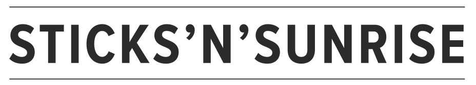 A logo featuring stylised black lettering with the text "Sticks' N' Sunrise". 